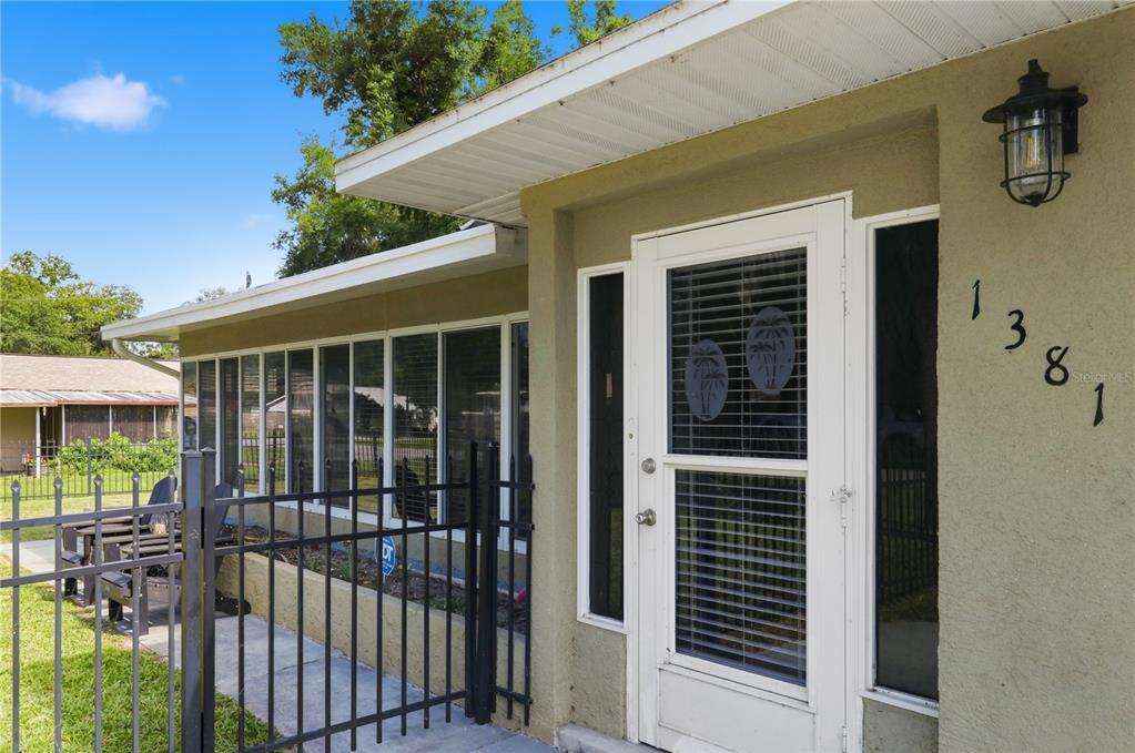 The exterior of a house features a white storm door, large windows, and black fencing — 1381 CR 446A, LAKE PANASOFFKEE, FL