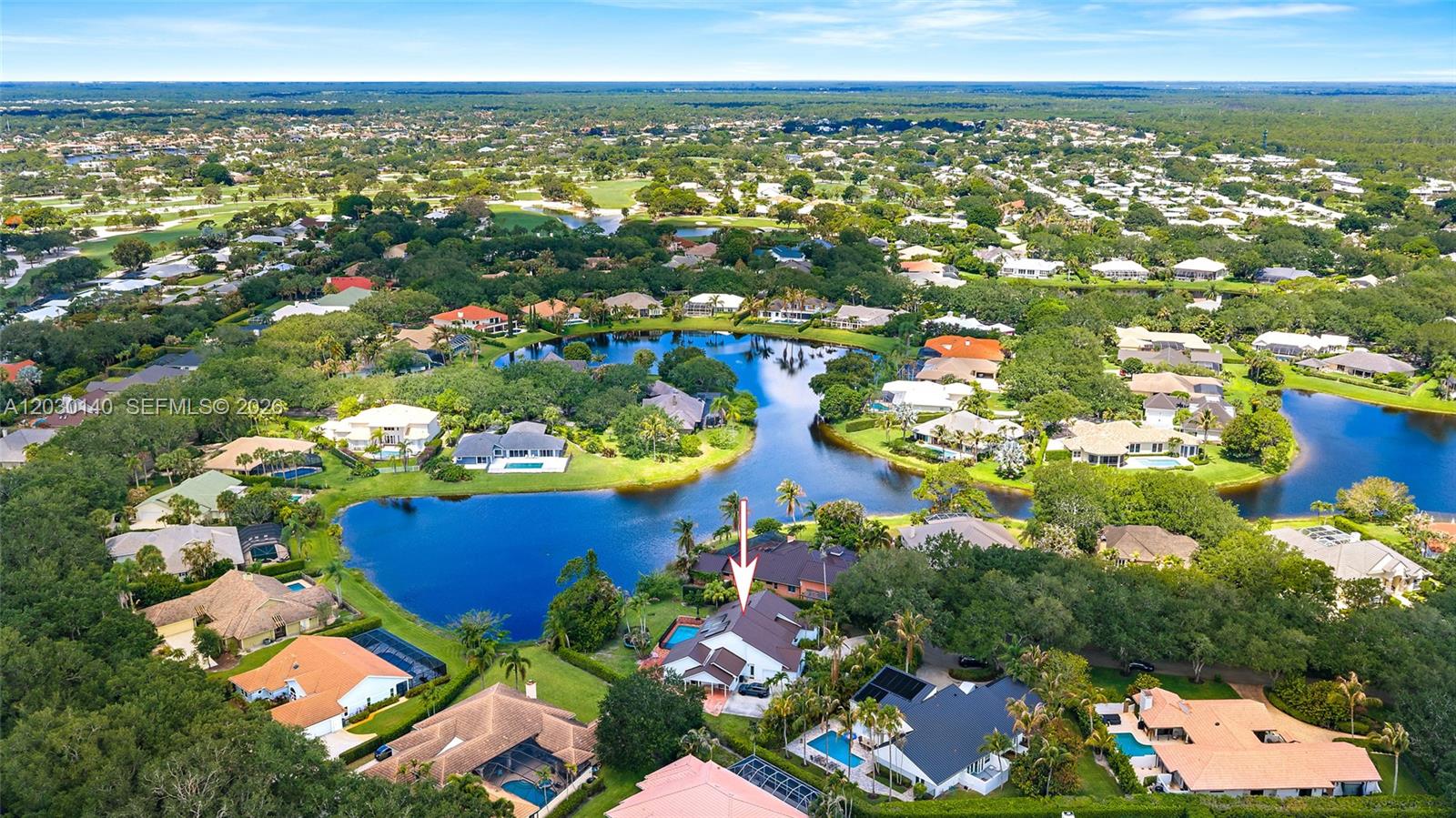 An aerial view shows a residential house with a pool situated near a lake — 10290 SE Banyan Way, Jupiter FL 33469, JUPITER, FL