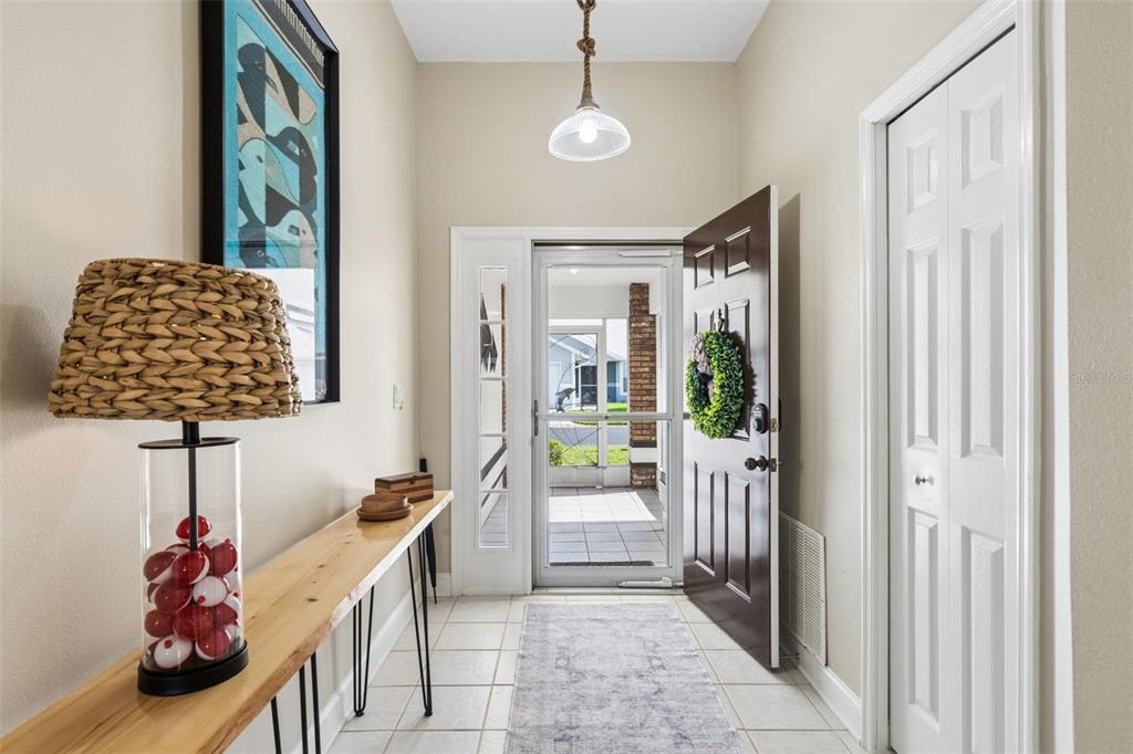 A bright entryway features a console table, a unique lamp, and a door leading outside — 452 SWEETWATER WAY, HAINES CITY, FL