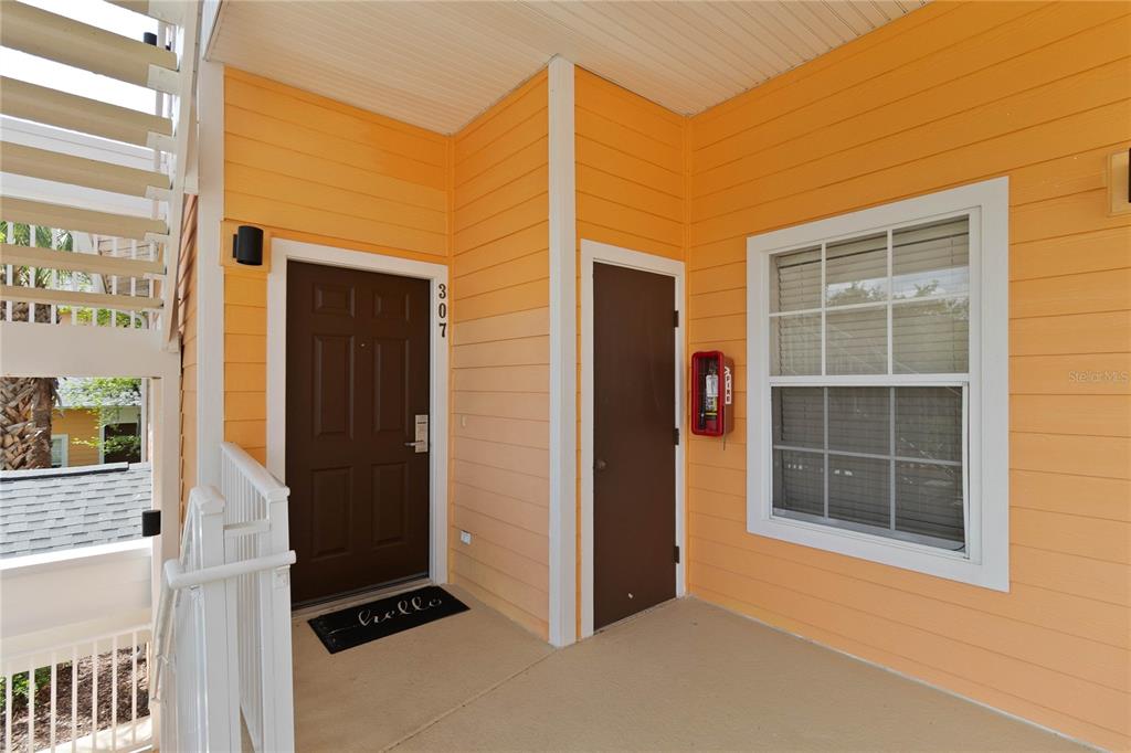 An exterior view of a building entrance with orange siding, two brown doors, and windows — 307 NEW PROVIDENCE PROMENADE UNIT 0, DAVENPORT, FL