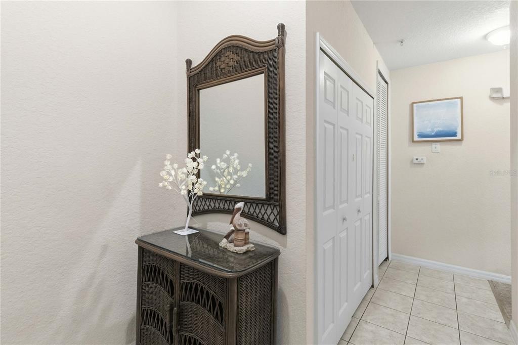 A hallway features a wicker cabinet with a matching mirror and a small decorative tree — 307 NEW PROVIDENCE PROMENADE UNIT 0, DAVENPORT, FL