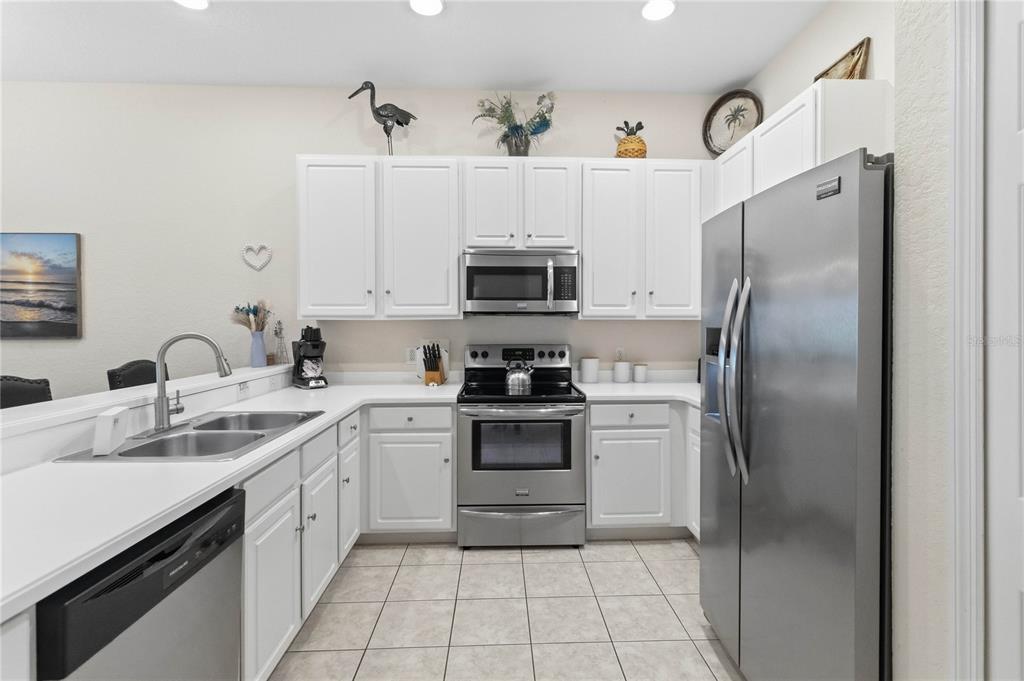 A kitchen features white cabinets, stainless steel appliances, a double sink, and tiled flooring — 307 NEW PROVIDENCE PROMENADE UNIT 0, DAVENPORT, FL