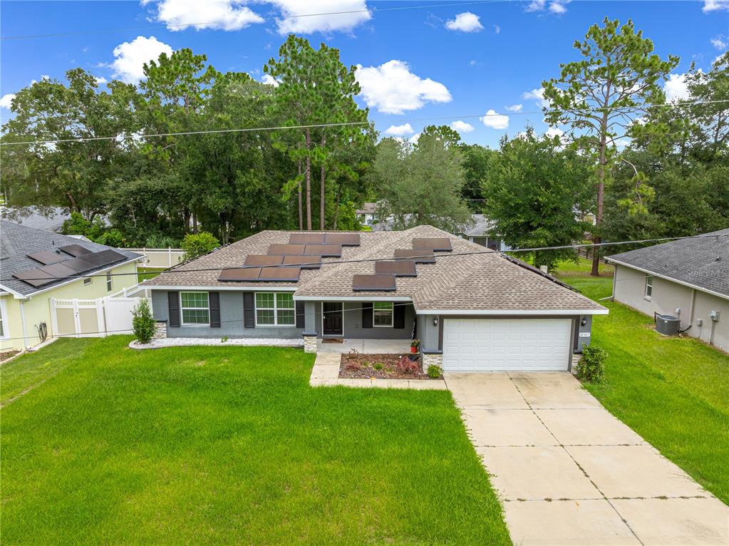 A single-story house with a gray exterior, a two-car garage, and solar panels on the roof — 8707 SE 161ST STREET, SUMMERFIELD, FL