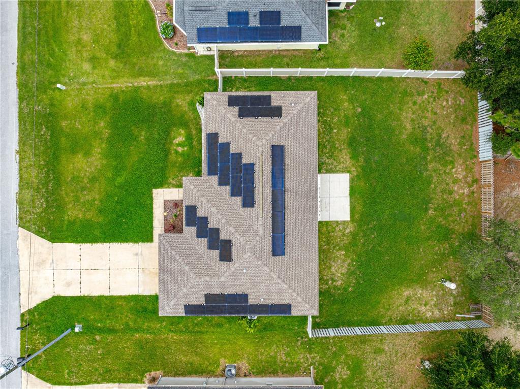 An aerial view shows a residential house with solar panels installed on its shingled roof — 8707 SE 161ST STREET, SUMMERFIELD, FL
