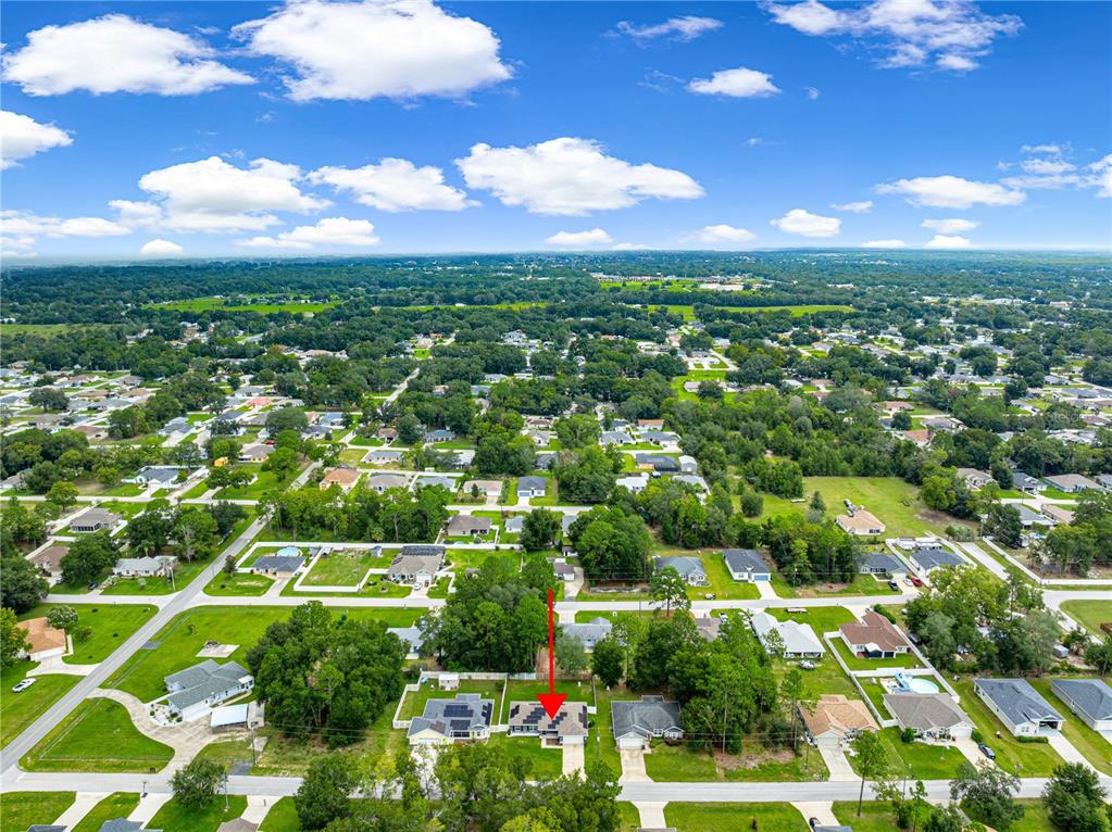 An aerial view shows a suburban neighborhood with a red arrow pointing to a house — 8707 SE 161ST STREET, SUMMERFIELD, FL