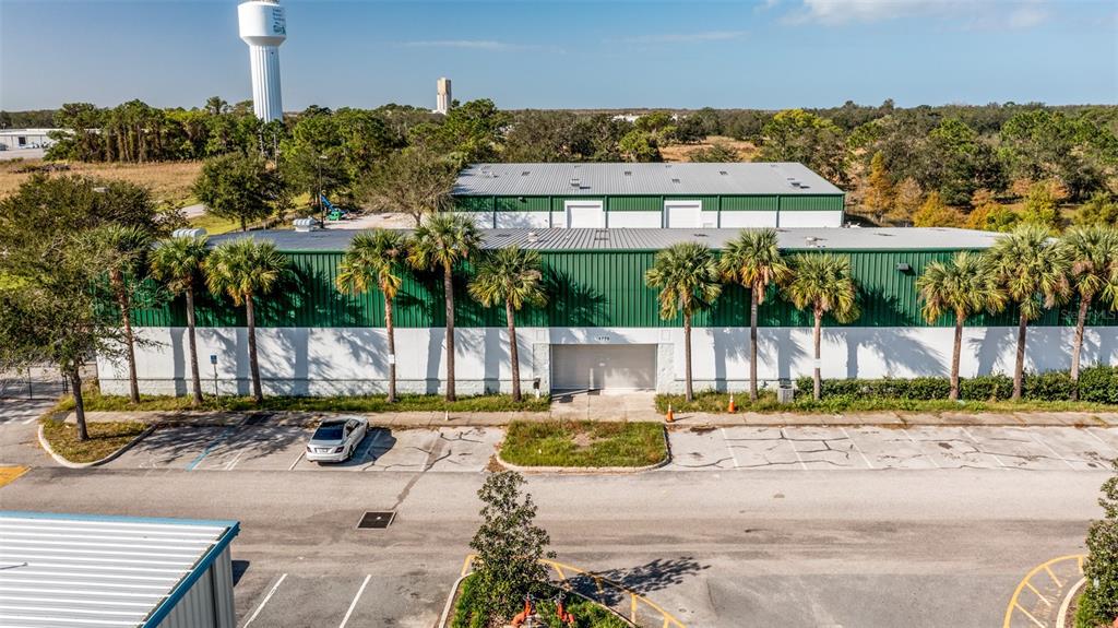 An exterior view of a green and white industrial warehouse building with a parking lot — 1770 BUSINESS CENTER LANE, KISSIMMEE, FL