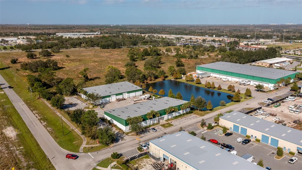 An aerial view shows several industrial warehouse buildings situated near a pond and open land — 1770 BUSINESS CENTER LANE, KISSIMMEE, FL