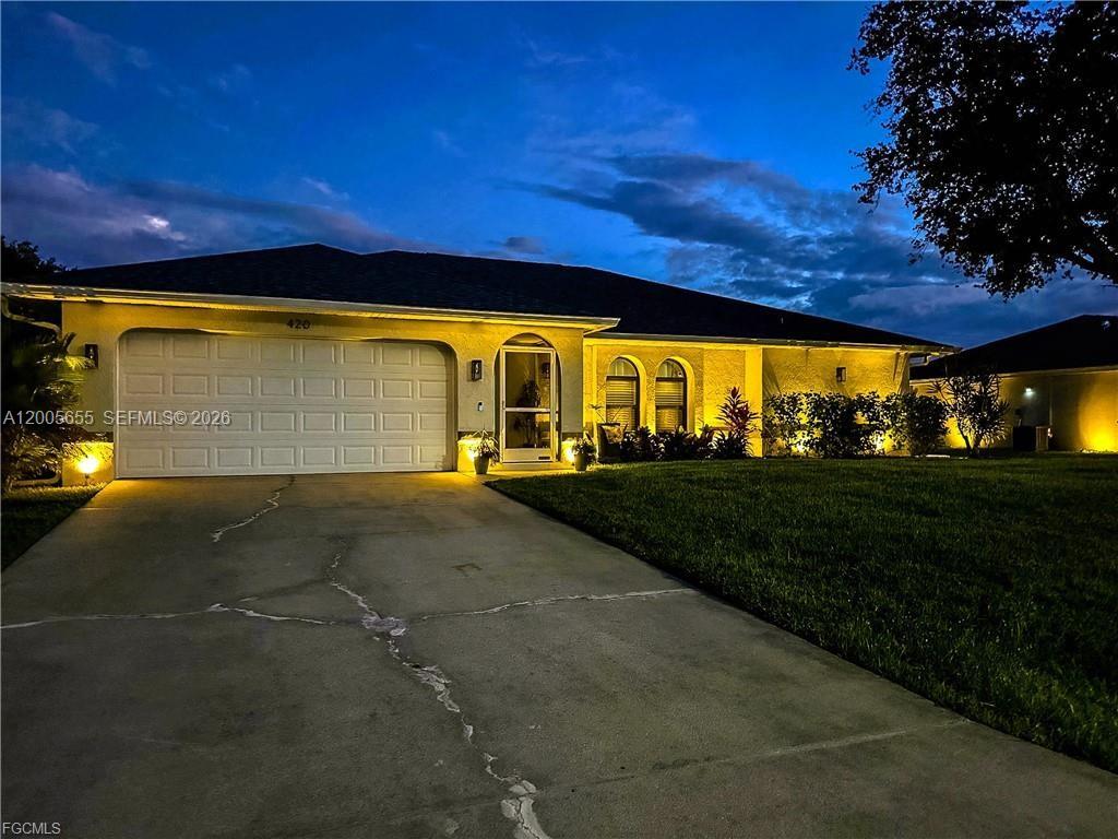 A single-story house with a two-car garage and a concrete driveway at twilight — CAPE CORAL, FL
