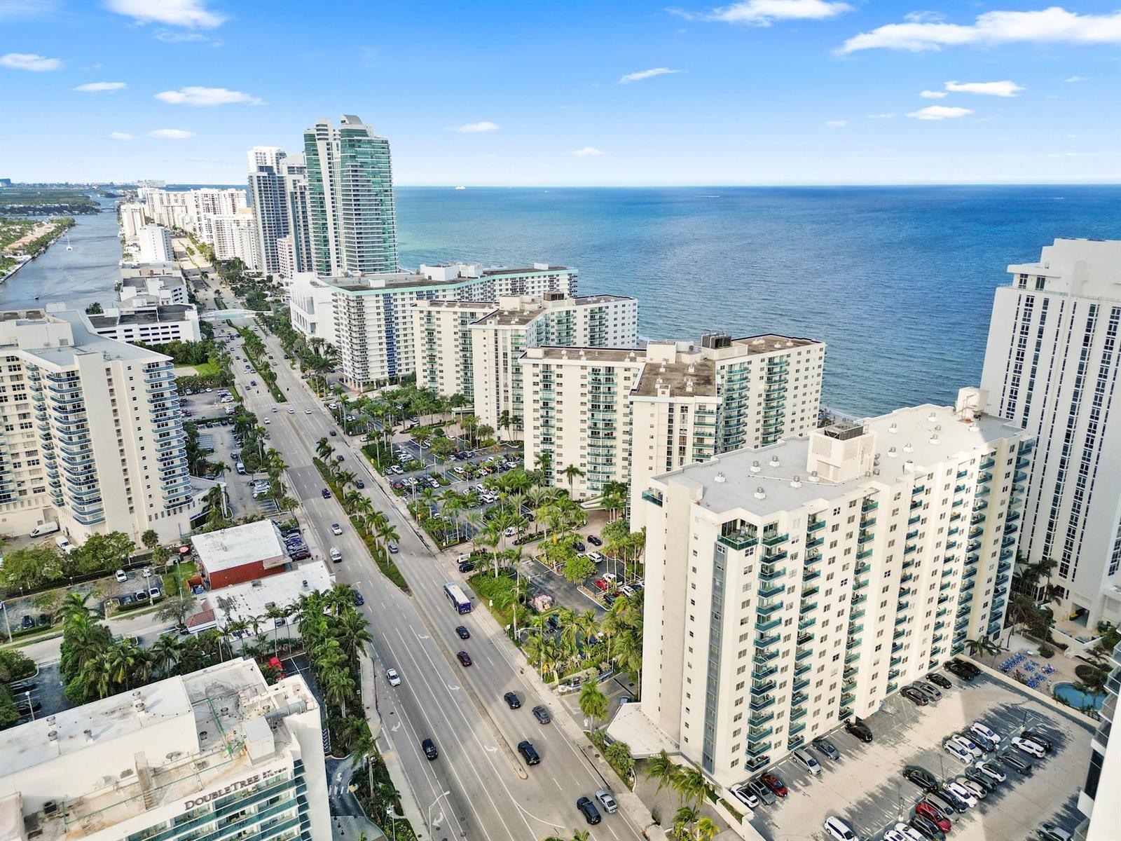 An aerial view shows high-rise apartment buildings along a coastal road next to the ocean — 4001 S Ocean Drive # 14D, Hollywood FL 33019, HOLLYWOOD, FL