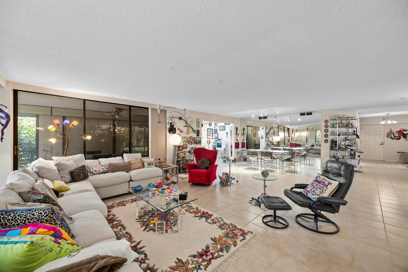 A spacious living room features tile flooring, a large white sectional, and a red armchair — 7209 Promenade Drive # 101, Boca Raton FL 33433, BOCA RATON, FL