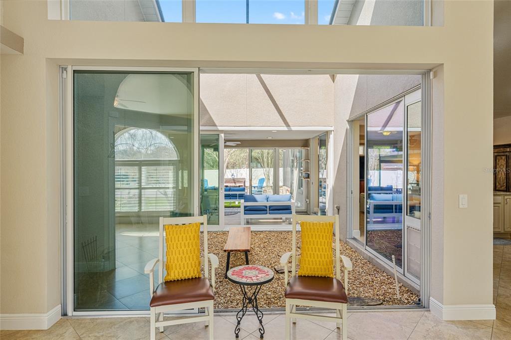 A view from a tiled room looking out into a central gravel courtyard with seating — 8353 SE 162ND STREET, SUMMERFIELD, FL