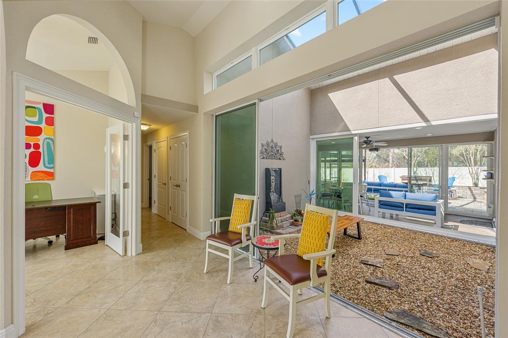 A bright room with tile floors, two chairs, and a glass-enclosed indoor rock garden — 8353 SE 162ND STREET, SUMMERFIELD, FL