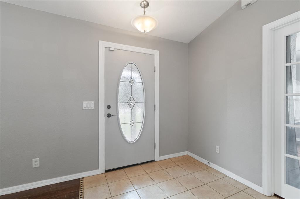 An entryway features light gray walls, a tiled floor, and a front door with glass — 3941 SANTA ANA ROAD, NORTH PORT, FL