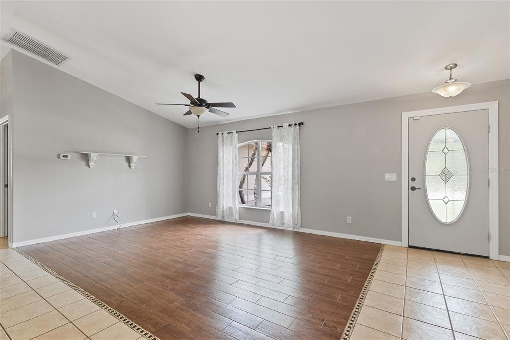 A living room features wood-look tile flooring, a ceiling fan, and a front entry door — 3941 SANTA ANA ROAD, NORTH PORT, FL