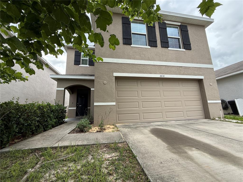 A two-story tan stucco house features a two-car garage and a covered front entryway — 6616 SEAWAY DRIVE, BROOKSVILLE, FL