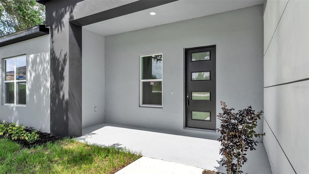 The exterior view shows a covered entryway with a gray front door and a window — 1479 HOLLY HILL ROAD, DAVENPORT, FL