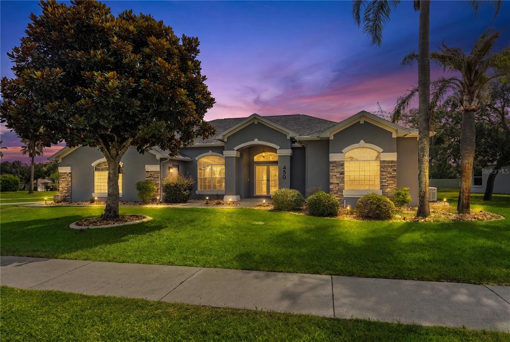 A single-story gray house with stone accents and a large tree in the front yard — 450 CASTILLE DRIVE, SPRING HILL, FL
