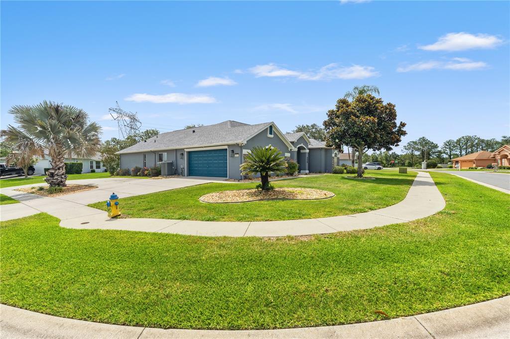 A gray single-story house with a blue garage door sits on a corner lot — 450 CASTILLE DRIVE, SPRING HILL, FL
