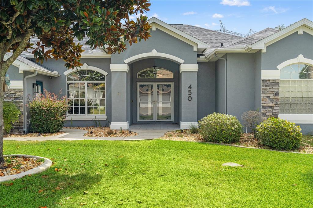 A gray house with a stone-accented facade, arched windows, and a double-door entryway — 450 CASTILLE DRIVE, SPRING HILL, FL