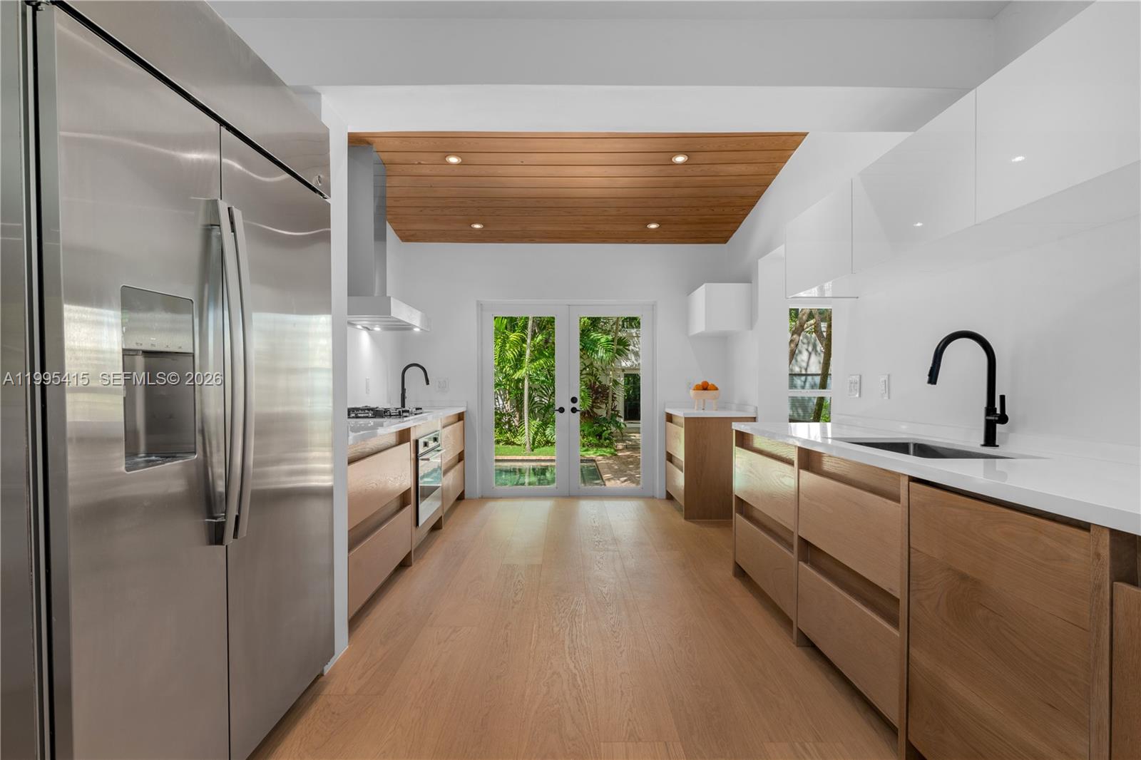 A modern kitchen features light wood cabinetry, white countertops, and a wood-paneled ceiling — 5812 Alton Rd, Miami Beach FL 33140, MIAMI BEACH, FL