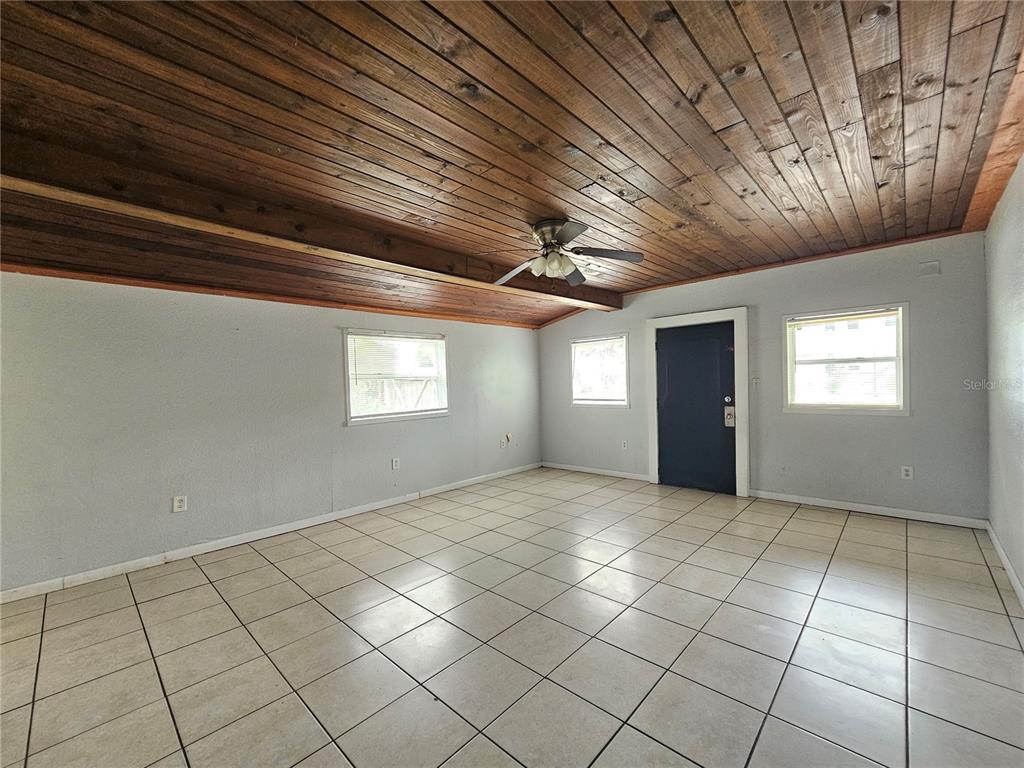 An empty room features a wood-paneled ceiling, light gray walls, and light-colored tile flooring — 1212 W MARJORIE STREET, LAKELAND, FL