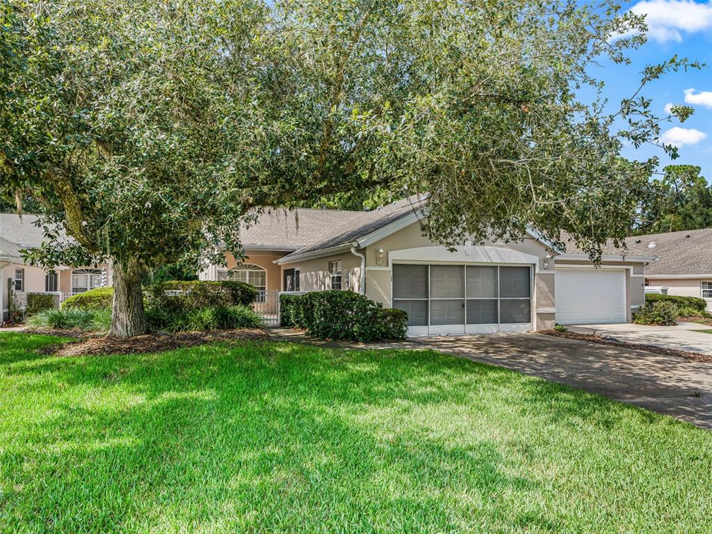 A single-story house with a screened garage, a large tree, and a green lawn — 7867 SW 115TH LOOP, OCALA, FL