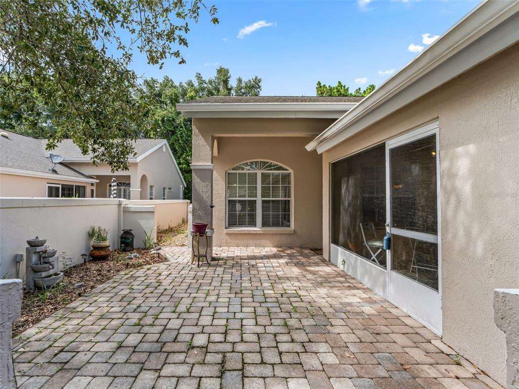 A paved patio sits outside a house with a screened-in porch and a privacy wall — 7867 SW 115TH LOOP, OCALA, FL