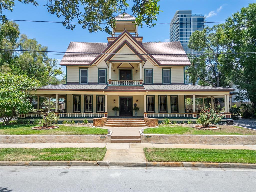 A two-story historic house with a wrap-around porch and a cupola sits behind a lawn — 3007 W STOVALL STREET, TAMPA, FL