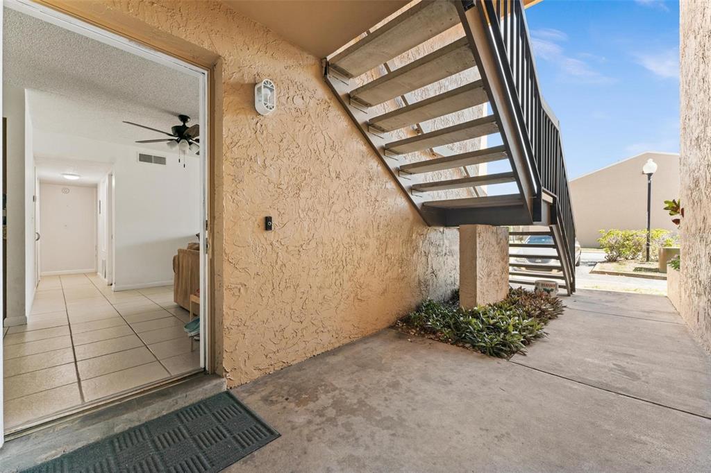 An exterior view of a ground-floor apartment entrance with a concrete patio and metal stairs — 5201 VINELAND ROAD UNIT 112, ORLANDO, FL