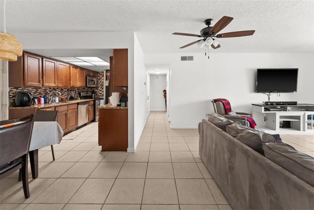 An open-concept living room and kitchen with tile flooring and a ceiling fan — 5201 VINELAND ROAD UNIT 112, ORLANDO, FL