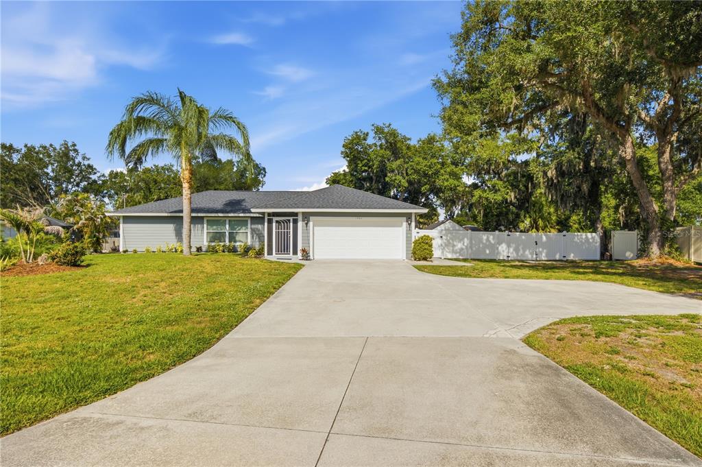A single-story house with gray siding, a white garage door, and a palm tree — 1964 PAR PLACE, SARASOTA, FL