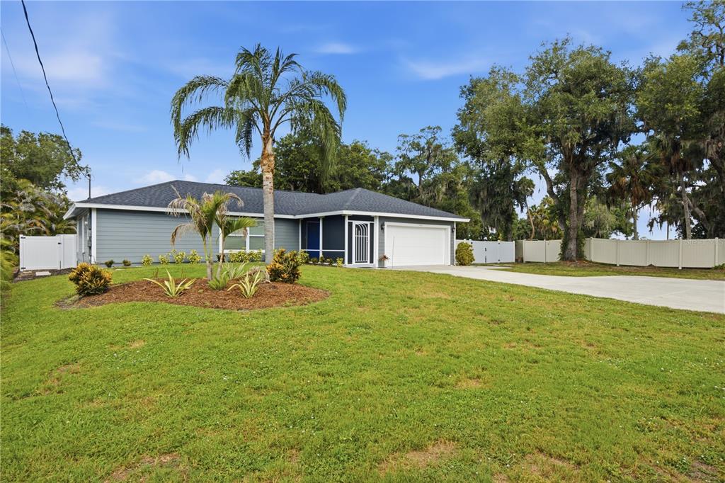 A single-story house with gray siding, a white garage door, and a palm tree in front — 1964 PAR PLACE, SARASOTA, FL