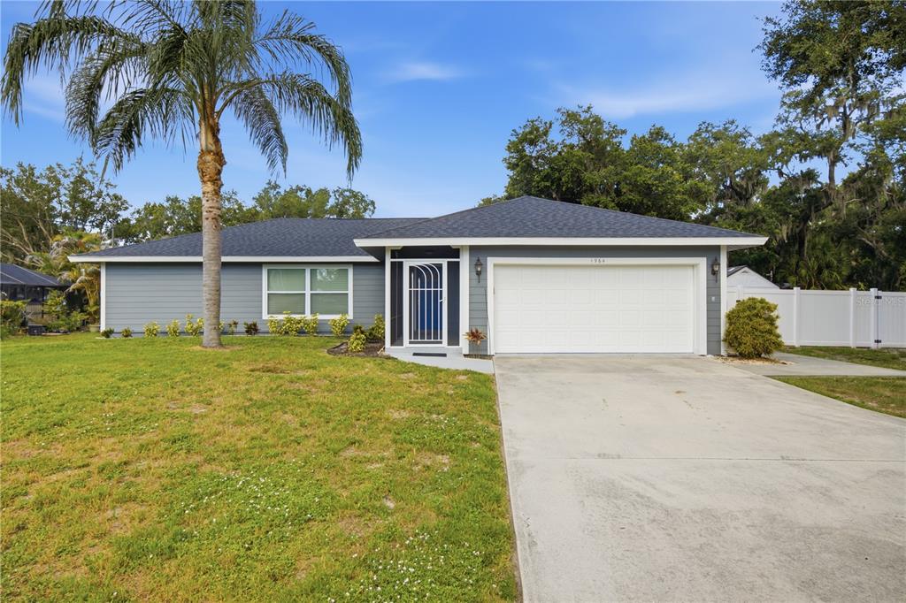 A single-story house with gray siding, a white garage door, and a palm tree — 1964 PAR PLACE, SARASOTA, FL
