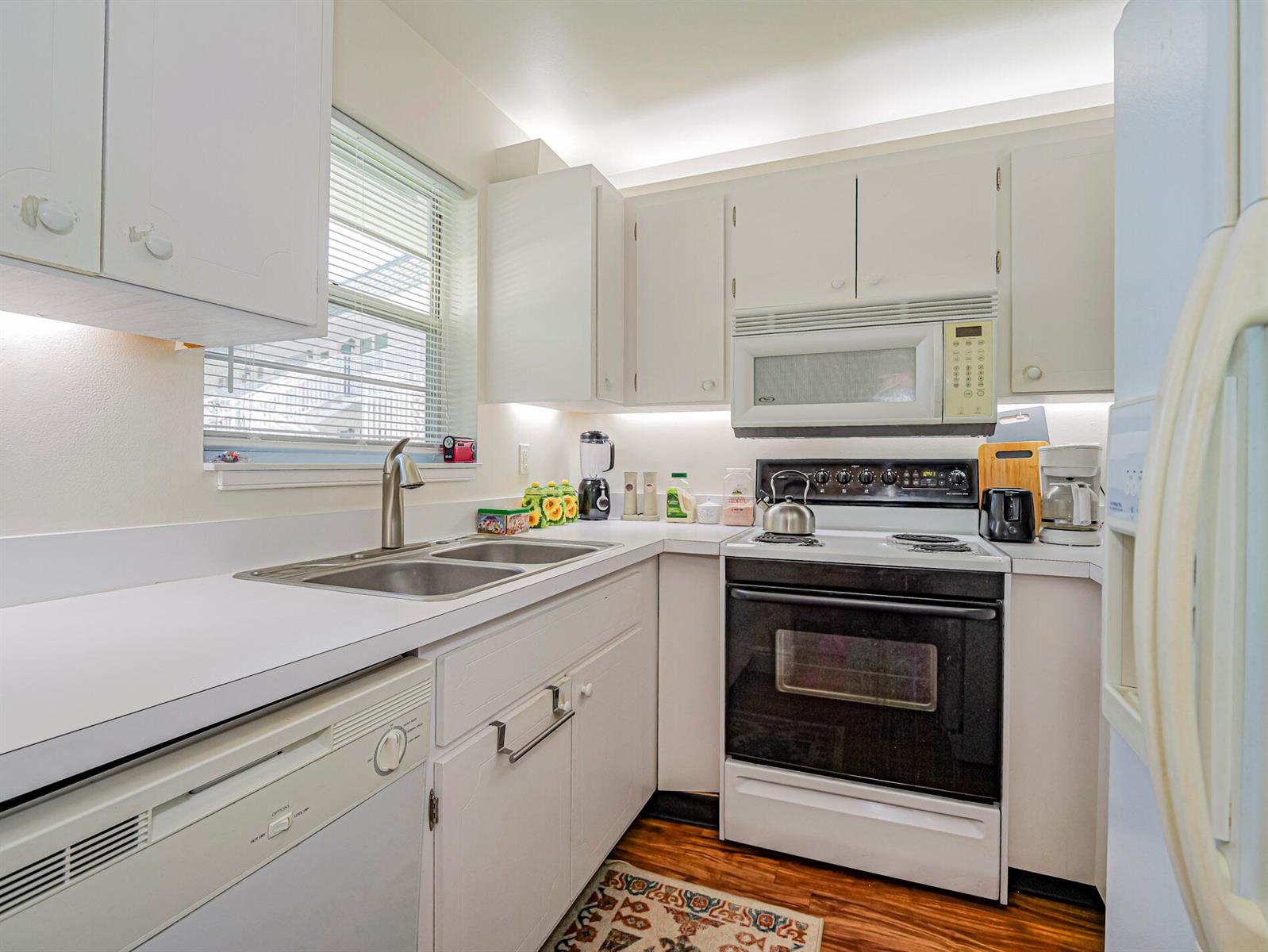A kitchen with white cabinets, white countertops, a stainless steel sink, and a black oven — 2800 Indian River Boulevard # 4r, Vero Beach FL 32960, VERO BEACH, FL