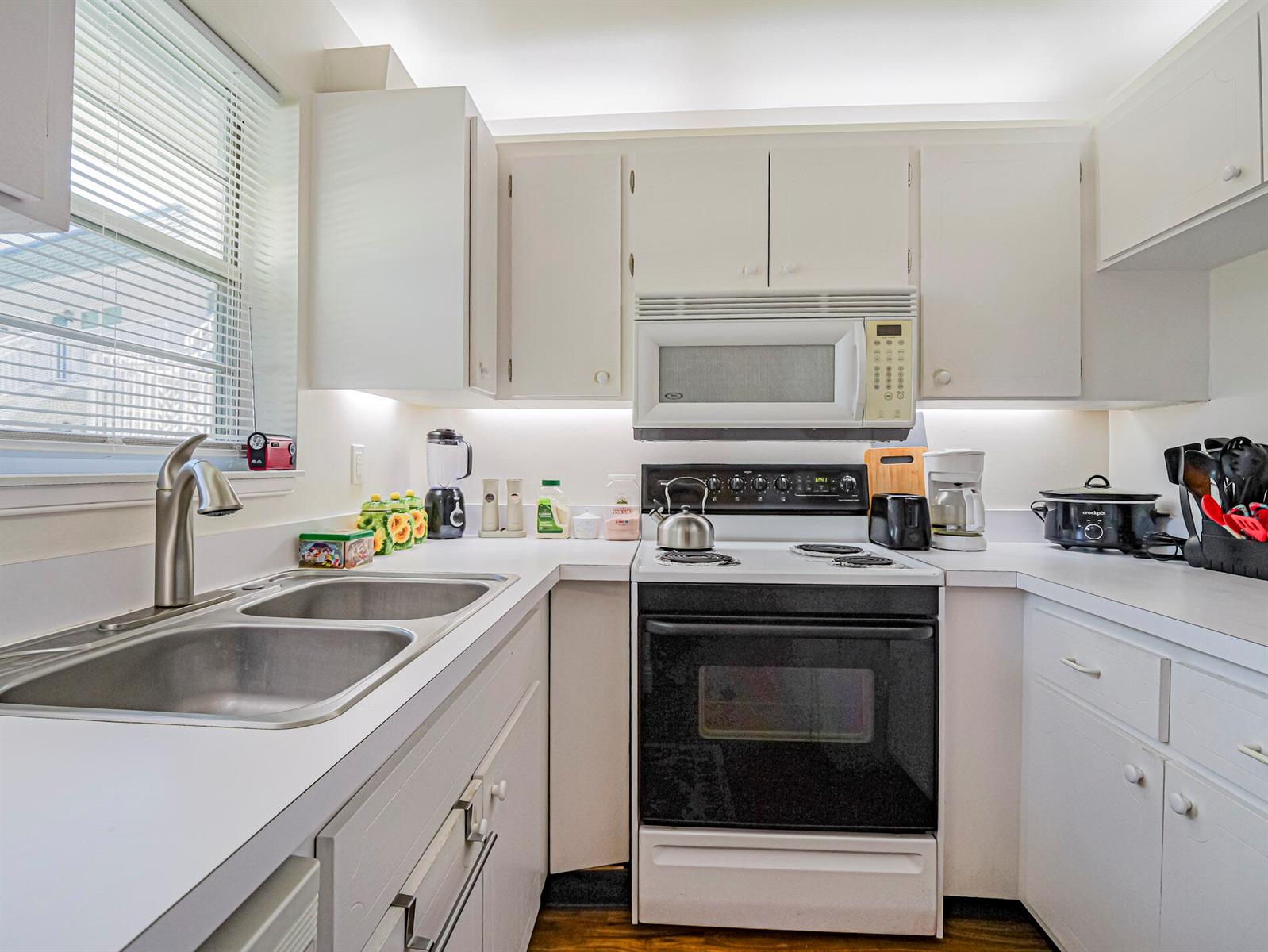 A kitchen features white cabinets, white countertops, a double sink, and black appliances — 2800 Indian River Boulevard # 4r, Vero Beach FL 32960, VERO BEACH, FL