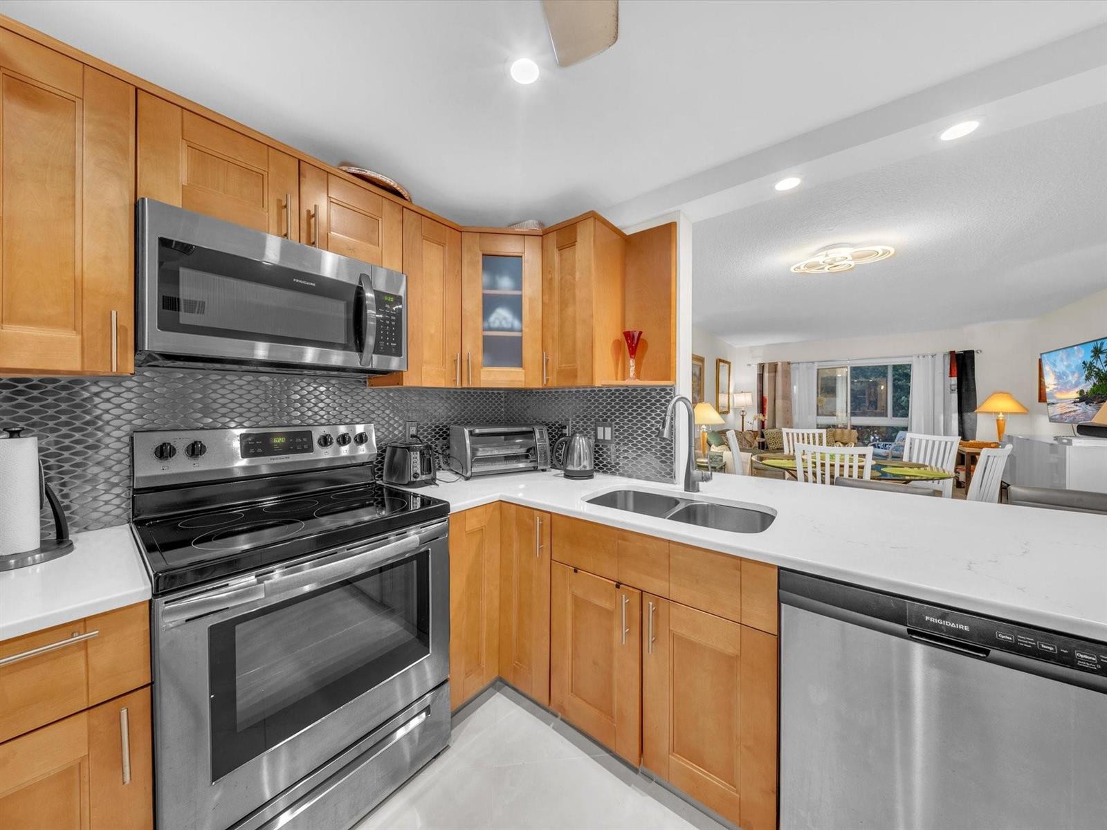 A kitchen with light wood cabinets, stainless steel appliances, and a gray tiled backsplash — 2515 NE 1st Court # 314, Boynton Beach FL 33435, BOYNTON BEACH, FL