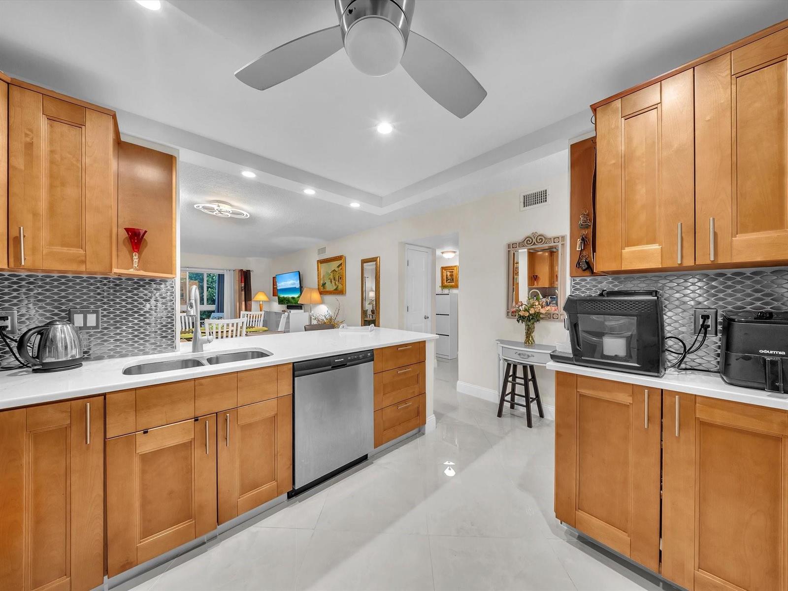 A kitchen with light wood cabinets, white countertops, stainless steel appliances, and a gray backsplash — 2515 NE 1st Court # 314, Boynton Beach FL 33435, BOYNTON BEACH, FL