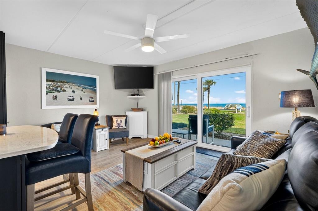 A living room features a leather sofa, coffee table, and sliding doors overlooking the beach — 2700 OCEAN SHORE BOULEVARD UNIT 106, ORMOND BEACH, FL