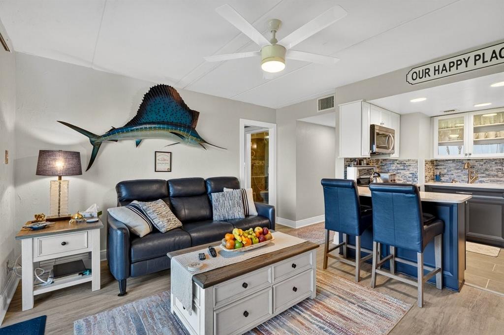 A living room and kitchen area feature a blue sofa, coffee table, and bar stools — 2700 OCEAN SHORE BOULEVARD UNIT 106, ORMOND BEACH, FL
