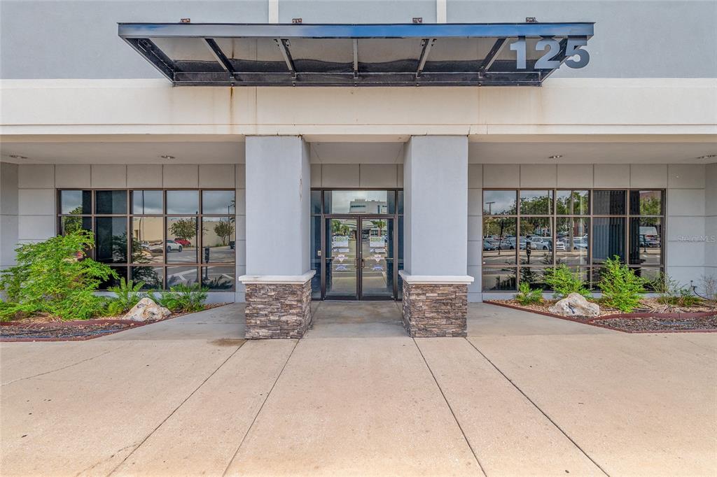 The exterior entrance of a commercial building features a glass door, stone pillars, and awning — 125 N 1ST AVENUE, OCALA, FL