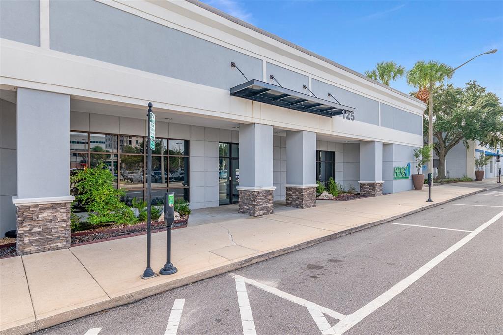The exterior of a commercial building features a concrete sidewalk, stone pillars, and glass windows — 125 N 1ST AVENUE, OCALA, FL