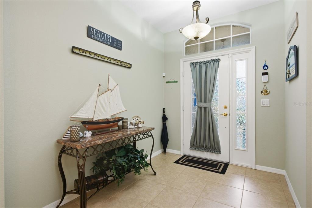 An entryway features a console table with a model ship, tile flooring, and a front door — 4882 W BREEZE CIRCLE, PALM HARBOR, FL