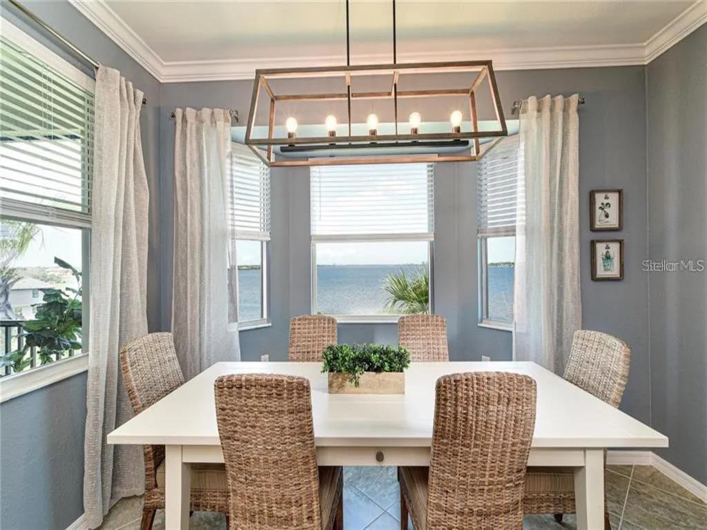 A dining room with a white table, wicker chairs, and a view of the water — 850 TIDEWATER SHORES LOOP UNIT 402, BRADENTON, FL