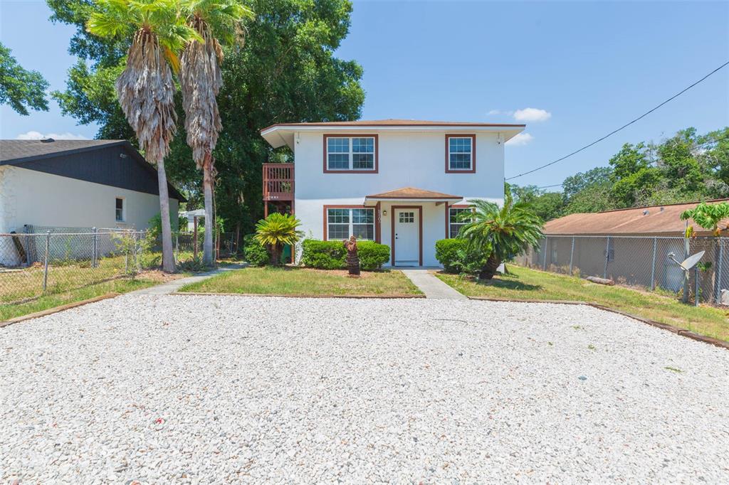 A two-story white house with brown trim features a gravel driveway and palm trees — 8510 N TAMPA STREET UNIT B, TAMPA, FL