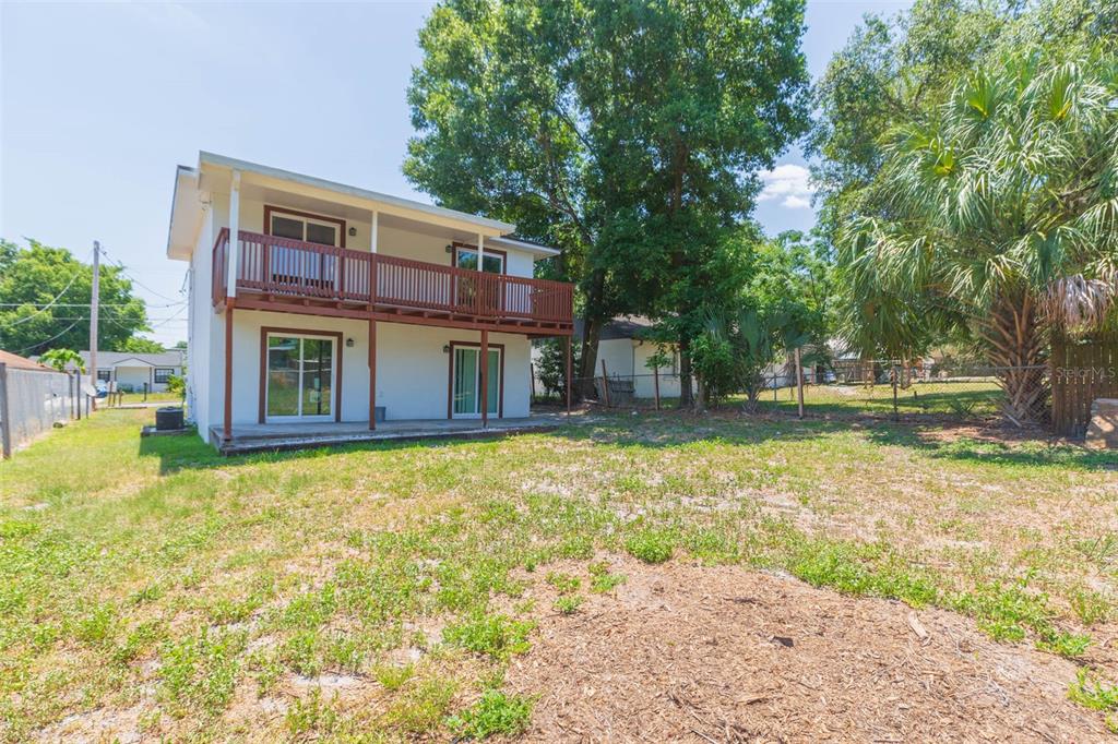 The exterior of a two-story house with a wooden balcony and a backyard — 8510 N TAMPA STREET UNIT B, TAMPA, FL