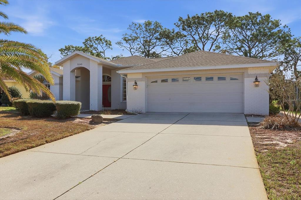 A single-story house with a white brick exterior, a two-car garage, and a concrete driveway — 9240 BUTLER BOULEVARD, WEEKI WACHEE, FL