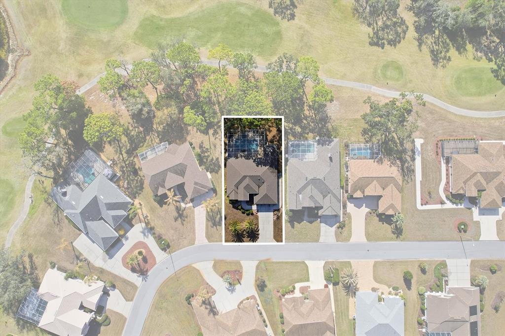 An aerial view shows a single-family home with a pool cage on a golf course — 9240 BUTLER BOULEVARD, WEEKI WACHEE, FL