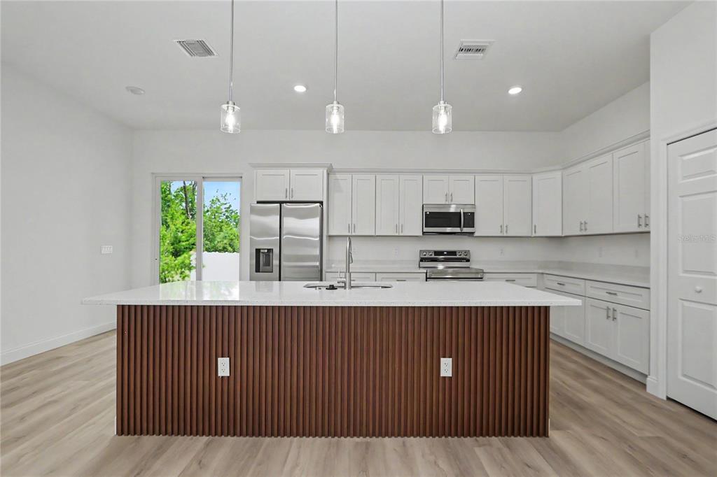 A kitchen features white cabinets, stainless steel appliances, and a wood-slatted kitchen island — 4814 SW 166TH LOOP, OCALA, FL