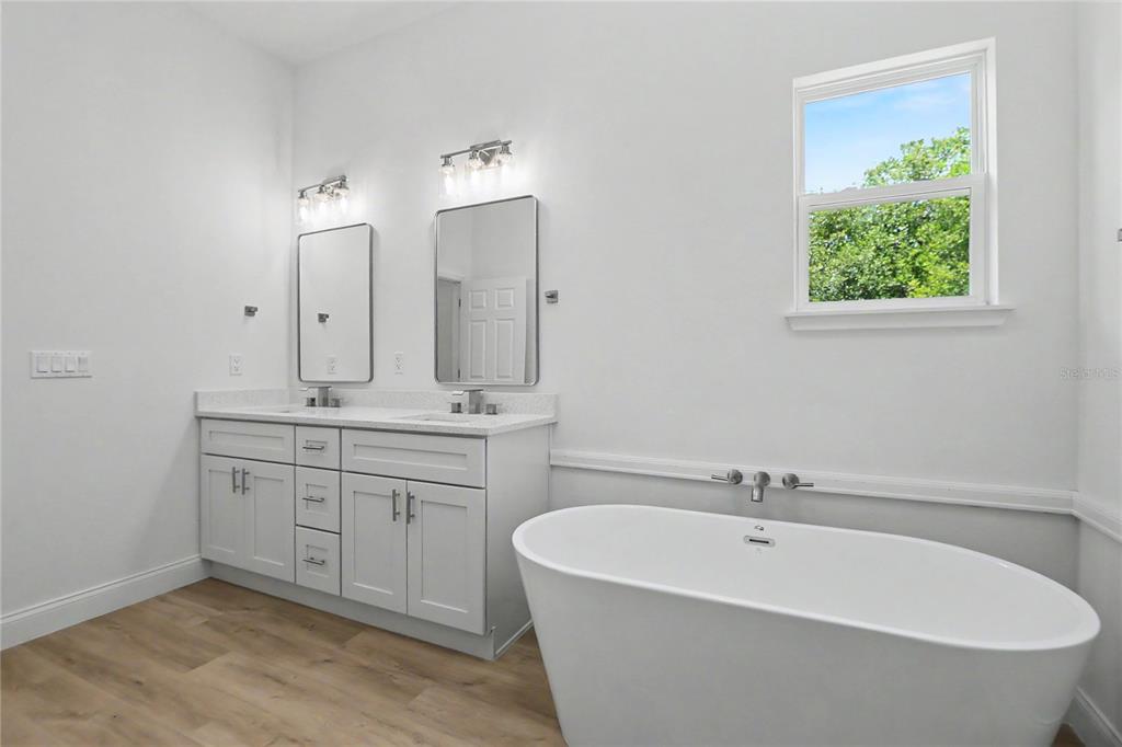 A bathroom features a double vanity with white cabinets, two mirrors, and a freestanding tub — 4814 SW 166TH LOOP, OCALA, FL