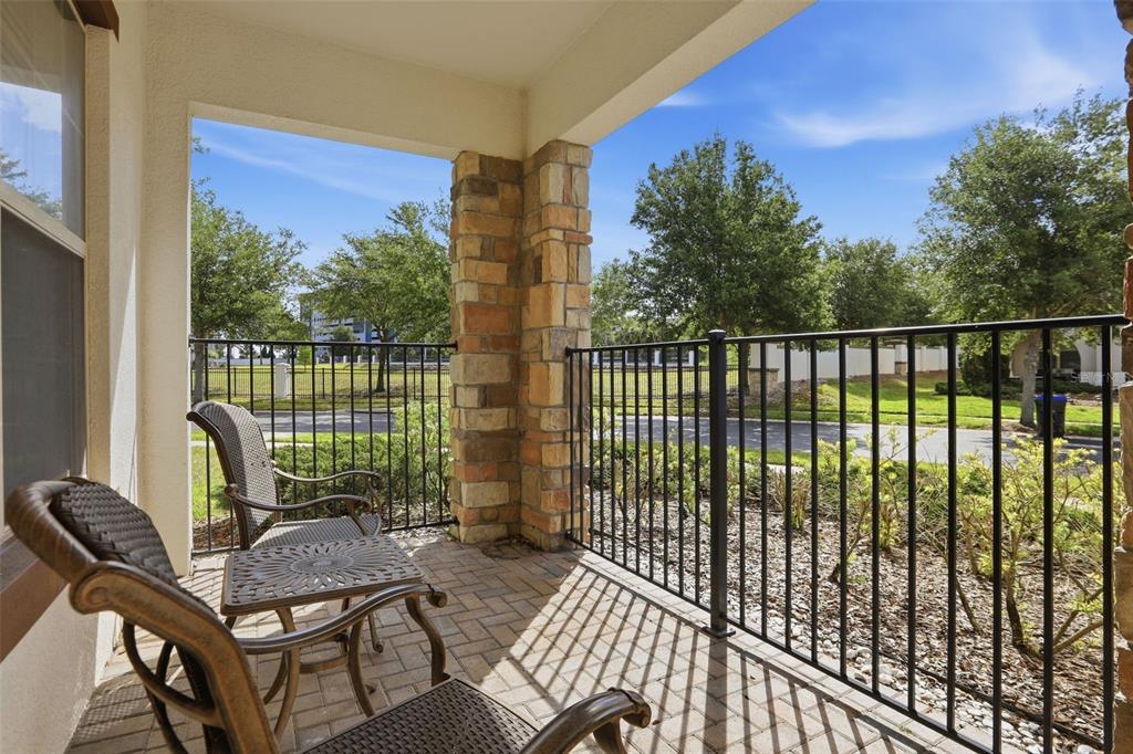 A covered patio with stone columns, a brick paver floor, and a black metal railing — 10902 CITRON OAKS DRIVE, ORLANDO, FL